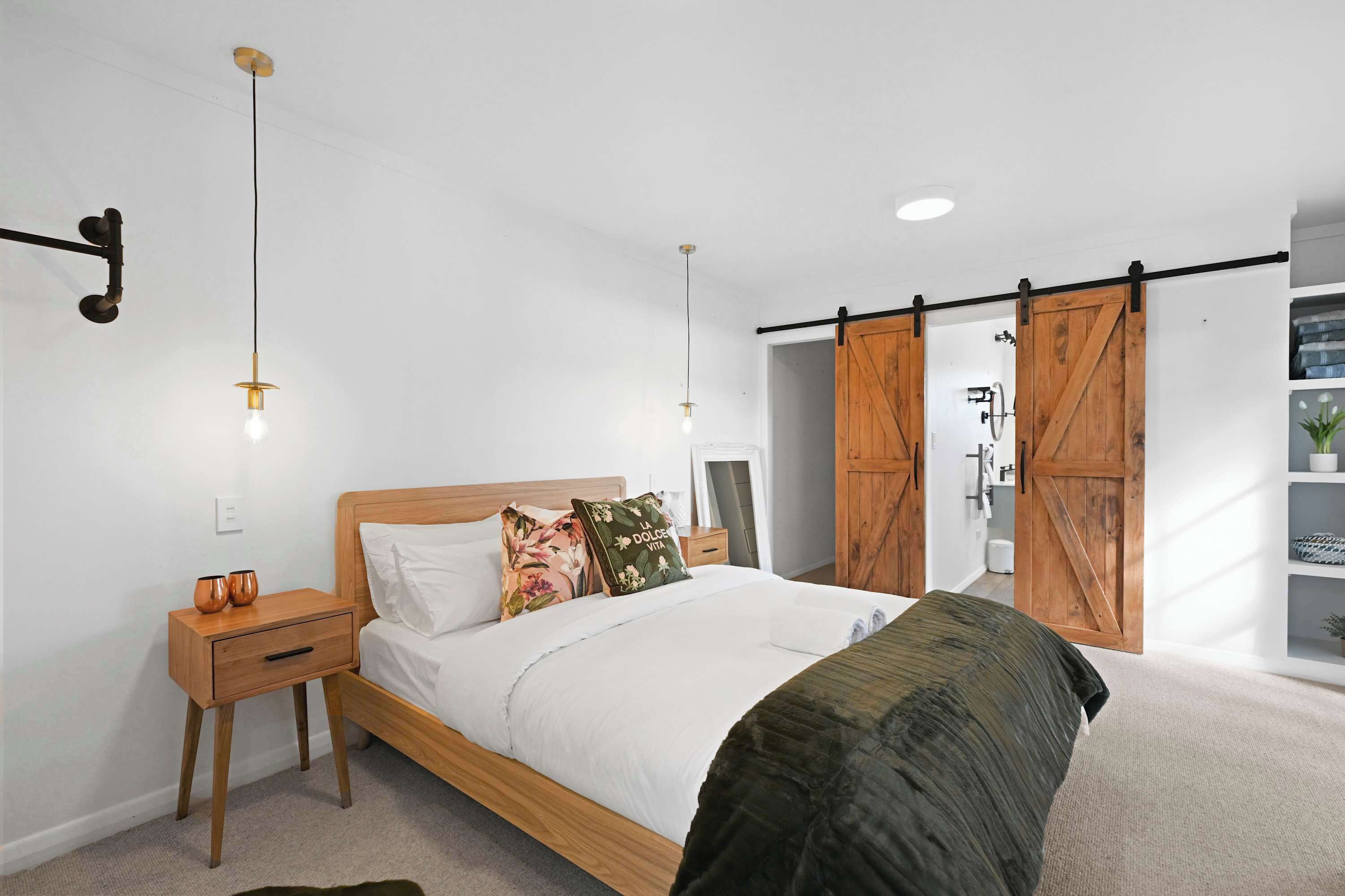 A bedroom with a bed, nightstand, and a sliding barn door closet.