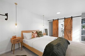 A bedroom with a bed, nightstand, and a sliding barn door closet.