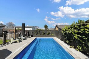 Una piscina rectangular amb aigua cristal·lina blava, envoltada d'un sòl de formigó i una tanca de fusta.