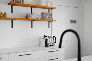 A kitchen with white cabinets, a coffee maker, and a pantry sign.