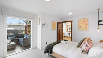 A bedroom with a bed, a sofa, and a view of the outside.