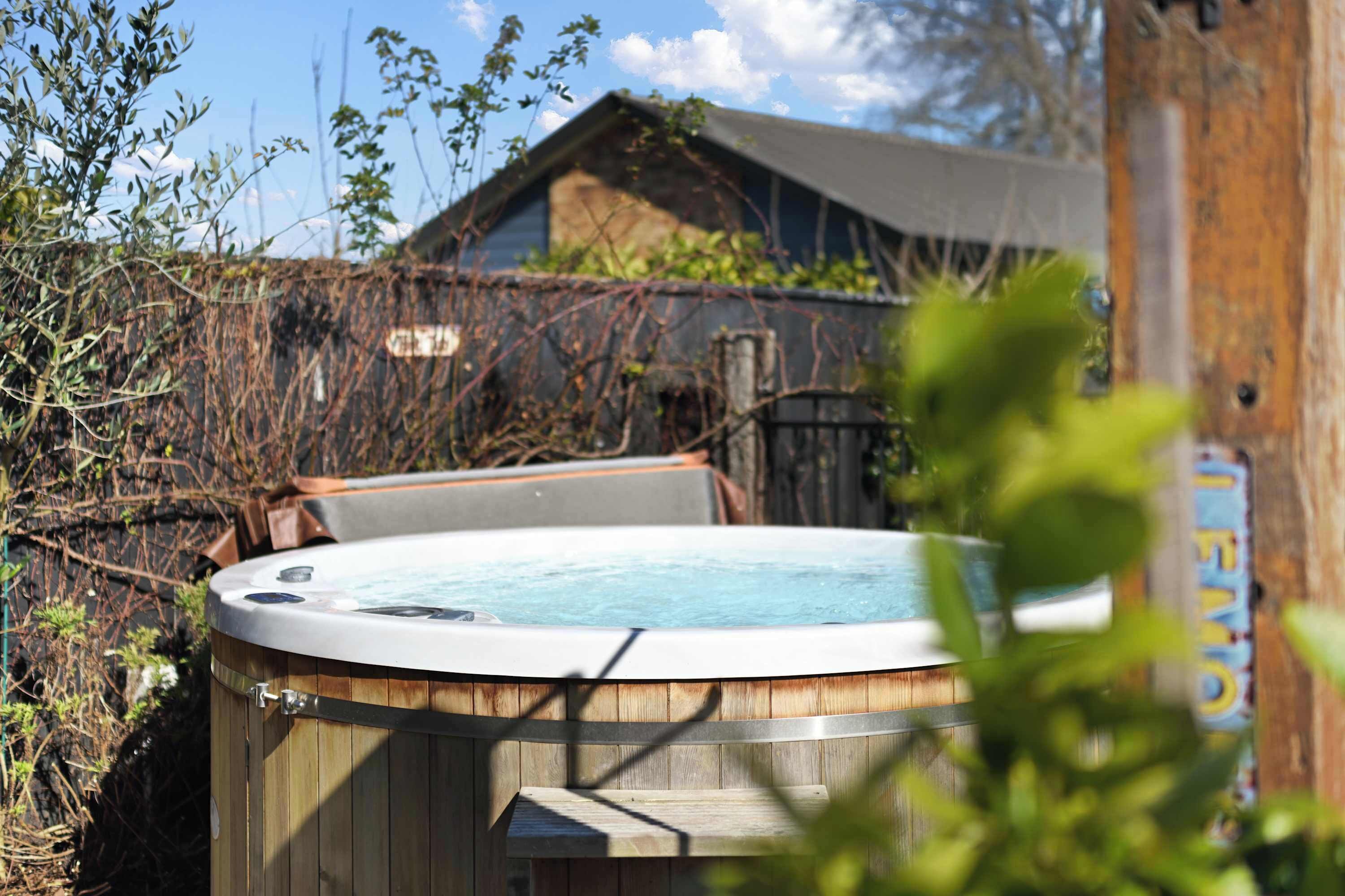 A hot tub in a wooden enclosure with a wooden deck in front.