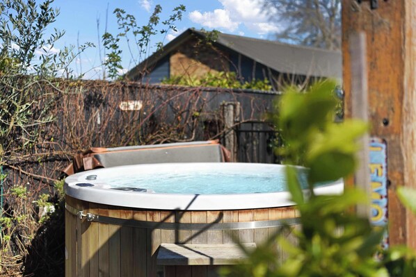 A hot tub in a wooden enclosure with a wooden deck in front.