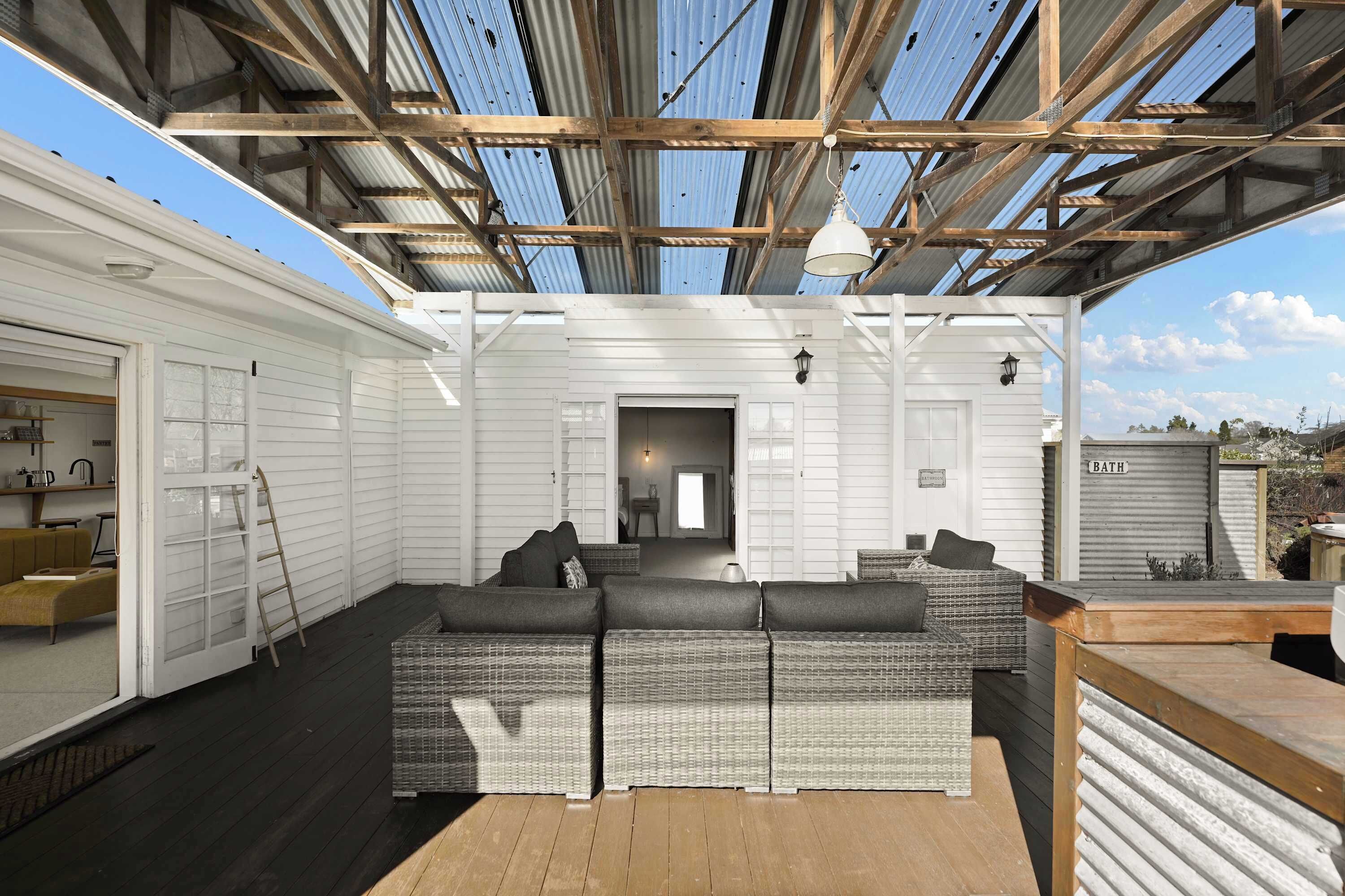 A covered outdoor seating area with a sofa and a wooden deck.