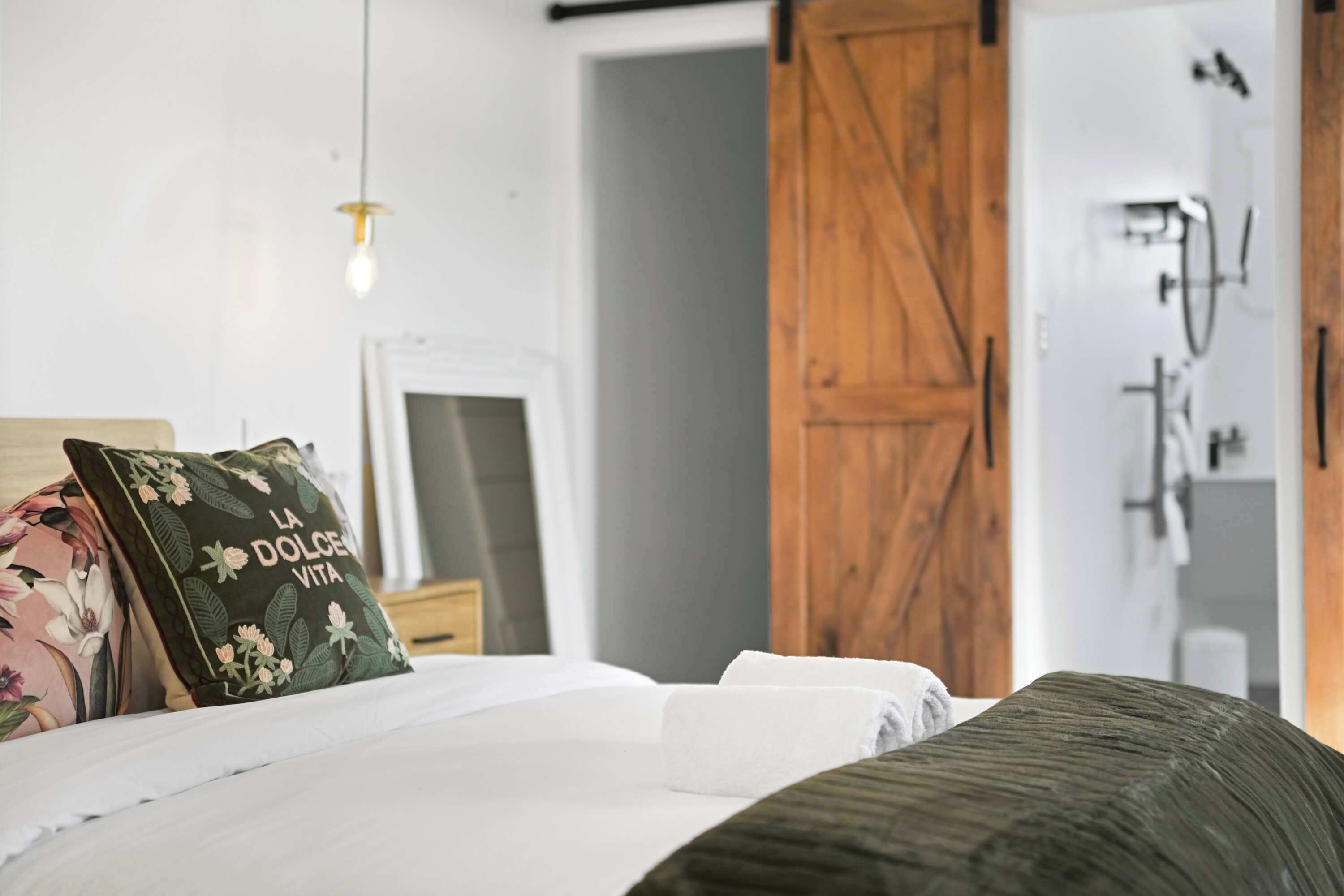 A bedroom with a bed, a wooden door, and a mirror.