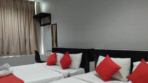 Ein Hotelzimmer mit zwei Betten, jeweils mit weißer Bettwäsche und roten Kissen, sowie einem Fenster mit Vorhängen.