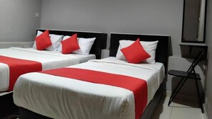 Ein Hotelzimmer mit zwei Betten, jeweils mit weißer Bettwäsche und roten Akzenten, einem schwarzen Stuhl und einem Spiegel an der Wand.