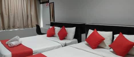A hotel room with two beds, each with white bedding and red pillows, and a red accent on the headboard.