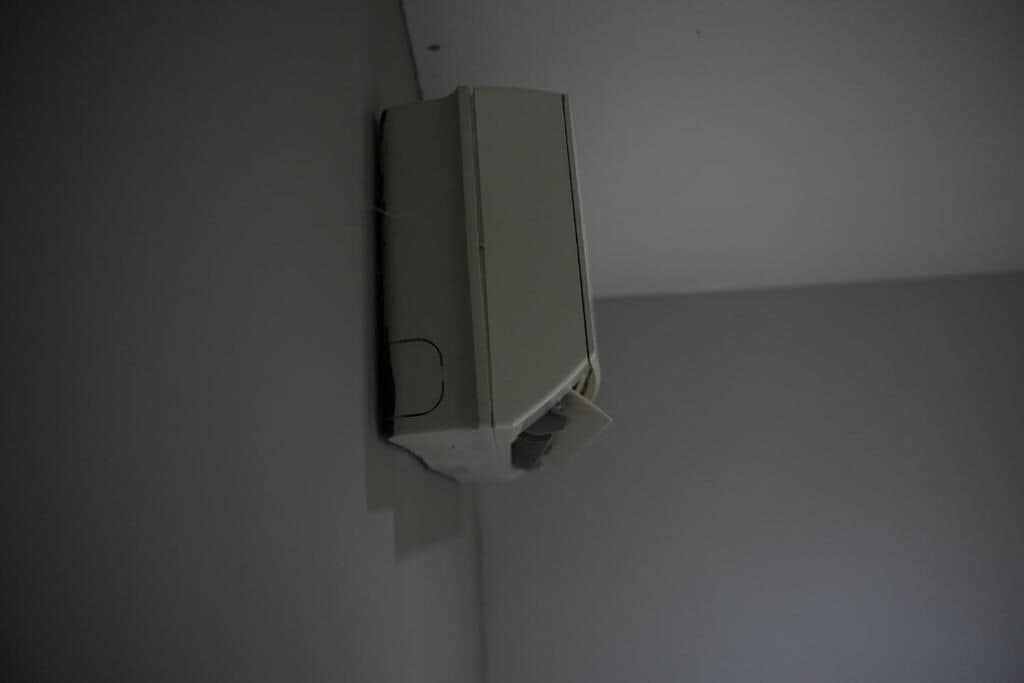 A white, rectangular object mounted on a wall, possibly a thermostat or control panel.