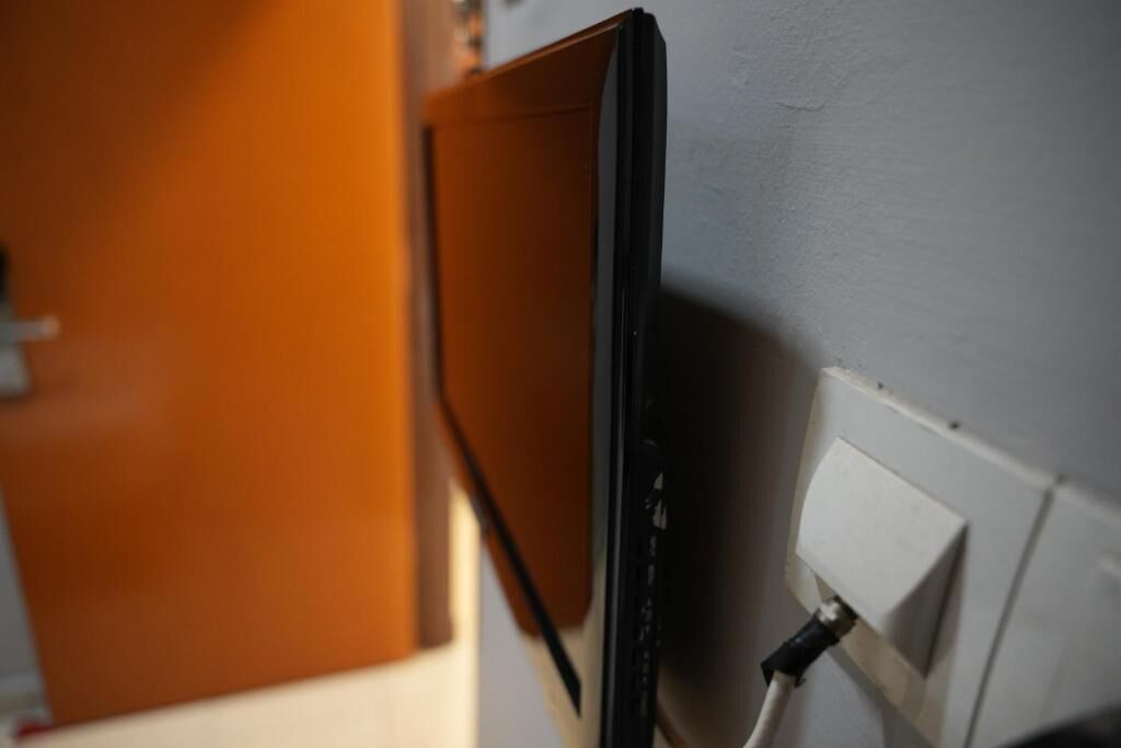 A wall-mounted television with a cable connected to a power outlet.