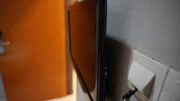 A wall-mounted television with a cable connected to a power outlet.