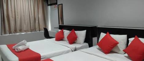 A hotel room with two beds, each with red and white bedding, and a window with curtains.