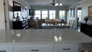 Una cocina amplia con una isla grande, comedor con sillas y un televisor montado en la pared.