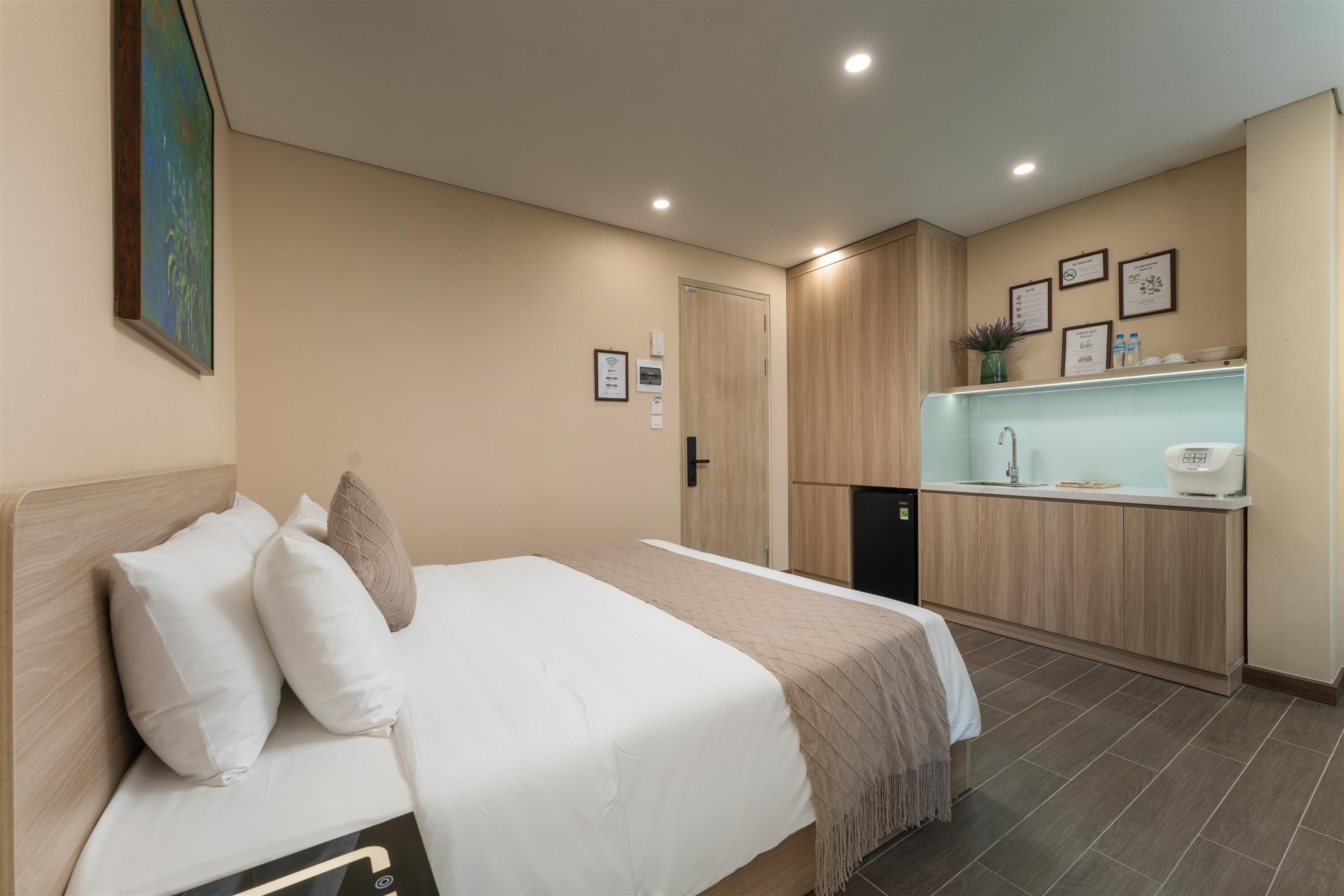 A hotel room with a bed, a kitchenette, and a bathroom.