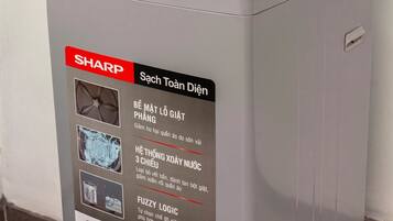 A SHARP washing machine with a control panel, a red label, and a QR code.