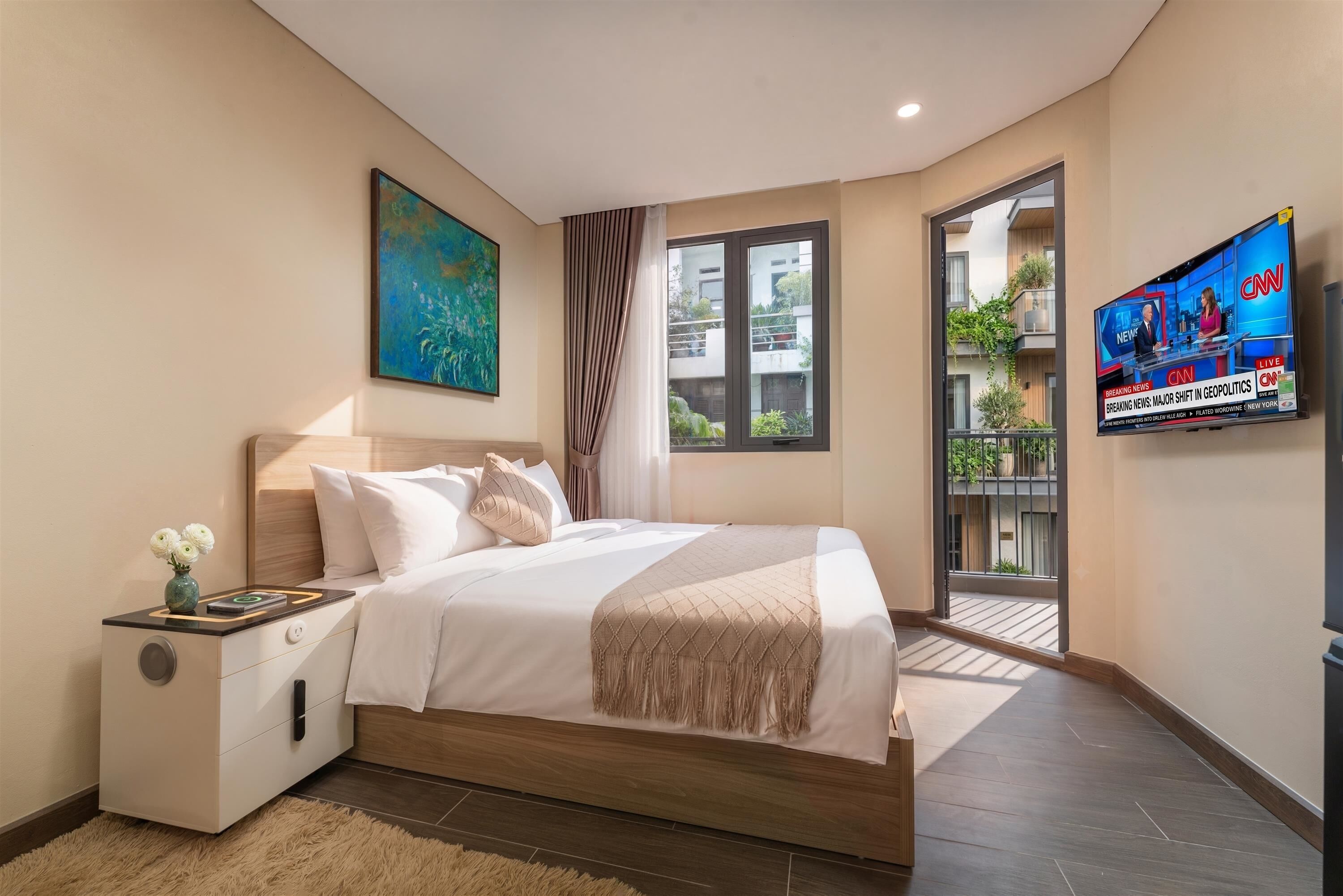 Une chambre à coucher moderne avec un lit, une table de chevet et un téléviseur diffusant les actualités.