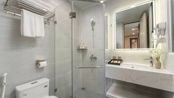 A modern bathroom with a glass-enclosed shower, a toilet, a towel rack, and a vanity with a mirror.
