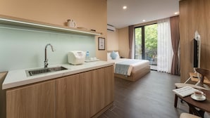 Une chambre d’hôtel équipée d’une kitchenette, d’un lit, d’un coin repas et d’une grande fenêtre avec des rideaux.