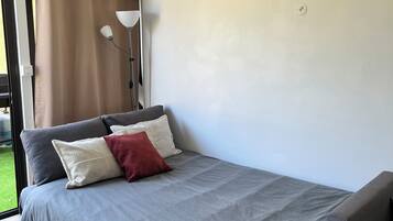 Une chambre à coucher moderne avec un lit gris, un oreiller rouge et un banc gris.