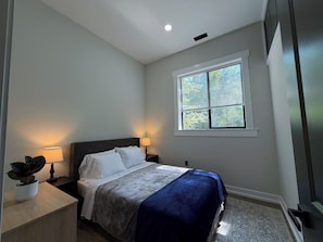 A bedroom with a bed, bedside lamps, a window, and a small plant. - Tall Pine Retreat — Cozy, Deep-Woods Getaway in tranquil Necedah (Necedah)