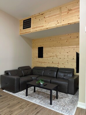 A modern living room with a sectional sofa, a coffee table, and a patterned rug. - Tall Pine Retreat — Cozy, Deep-Woods Getaway in tranquil Necedah (Necedah)