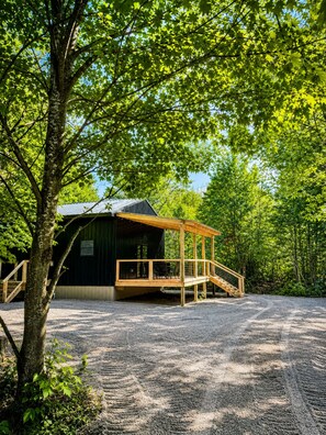 Un chalet rustique doté d’une terrasse en bois et d’un escalier menant à une zone abritée.