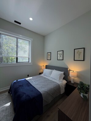 A bedroom with a bed, bedside lamps, a window with blinds, and wall art. - Tall Pine Retreat — Cozy, Deep-Woods Getaway in tranquil Necedah (Necedah)