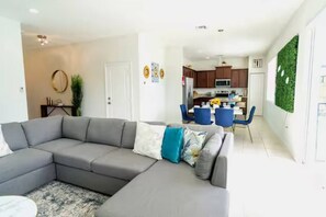 A modern living room with a grey sectional sofa, a small round table, and a decorative wall.