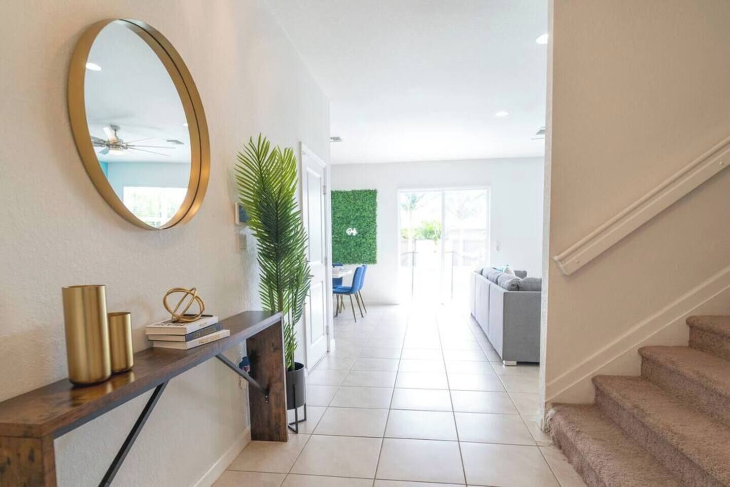 A modern interior with a staircase, a console table with decorative items, a large mirror, and a green wall.