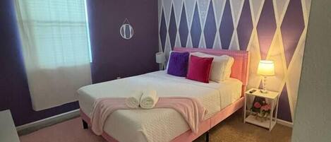 A bedroom with a bed, a ceiling fan, a nightstand, and a window with blinds.
