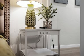 A table with a lamp, a small potted plant, and a power strip.