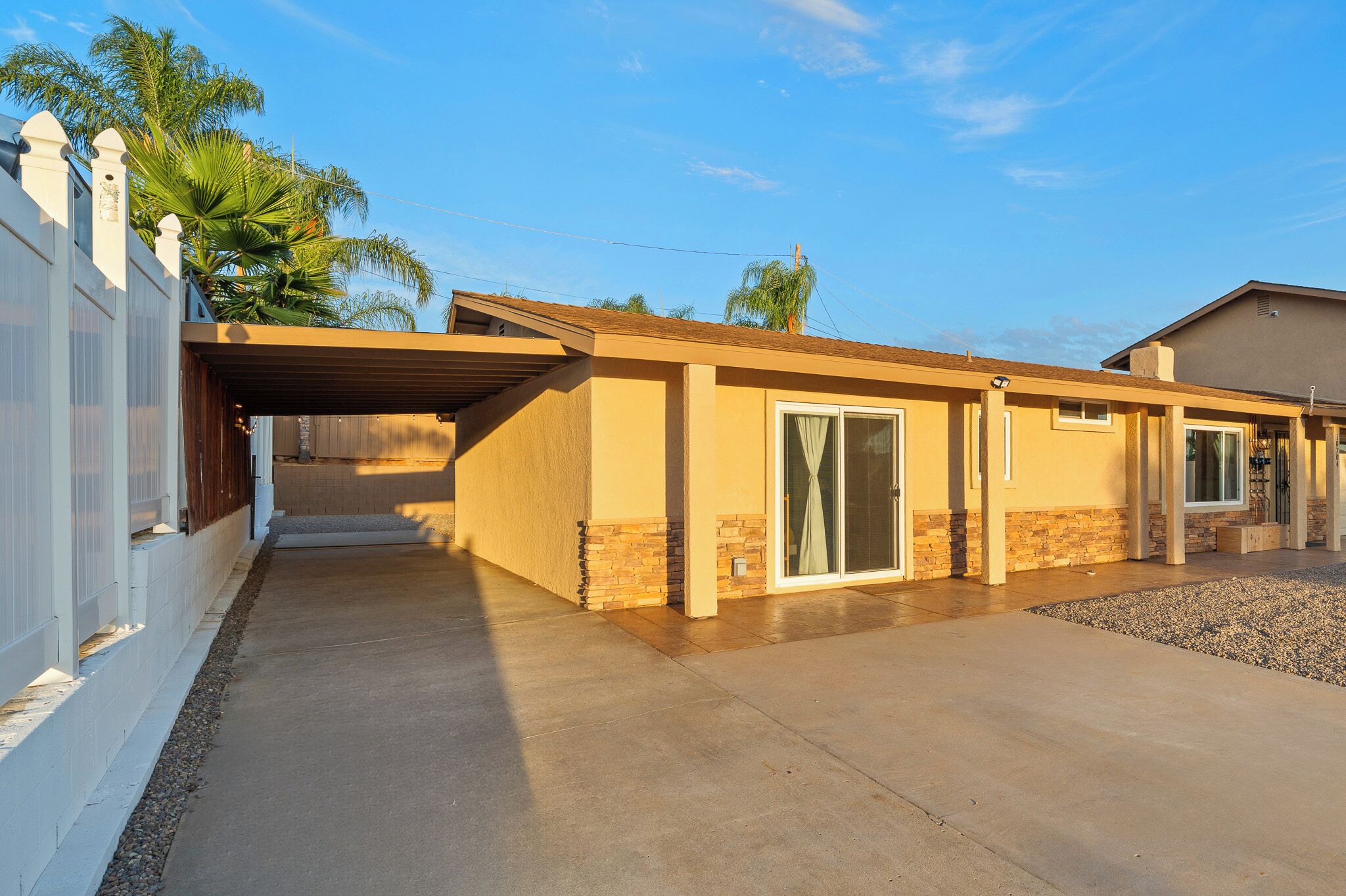 A single-story house with a covered patio, a stone foundation, and a garage.