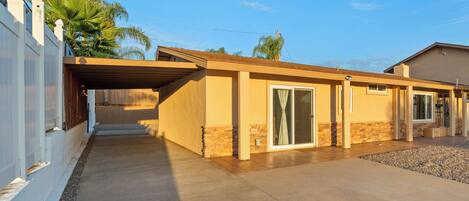A single-story house with a covered patio, a stone foundation, and a garage.