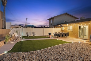 A backyard with a patio, seating area, and a grill.