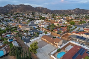 A residential area with houses, a swimming pool, and mountains in the background.
