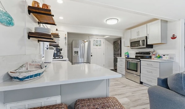 A modern kitchen with white cabinetry, a stainless steel refrigerator, and a microwave.