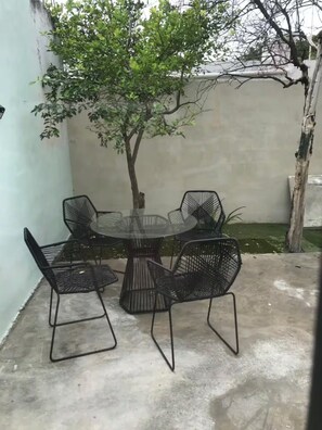 A small outdoor seating area with a round table and four chairs, surrounded by a low wall and a tree. - Casa FRIDA25 (Chelem)