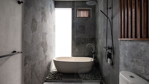 A modern bathroom with a freestanding bathtub, a shower, and a toilet.