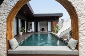 Ein Pool mit einer Holzbogenkonstruktion, einer Rutsche und einem modernen Gebäude mit großen Fenstern und einer Treppe.