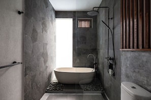 Een moderne badkamer met een vrijstaand bad, een douche en een toilet.
