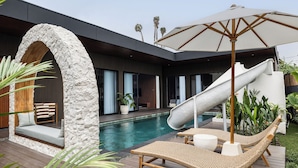 A modern house with a pool, a slide, and outdoor seating.