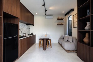 A modern kitchen with wooden cabinets, a black refrigerator, a marble countertop, and a central island with stools. - Villa BAB 36 (Tabanan)