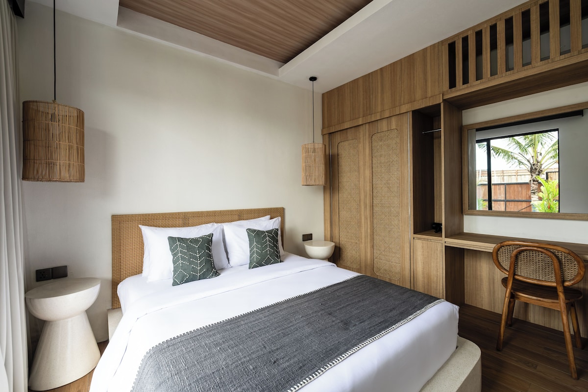 A modern hotel room with a large bed, bedside tables, a window with a view, and a wooden ceiling.