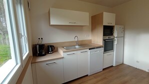 A modern kitchen with white cabinetry, a built-in oven, a microwave, and a sink.