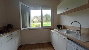 Une cuisine de taille réduite, dotée d’une fenêtre, d’un évier et d’une cuisinière.