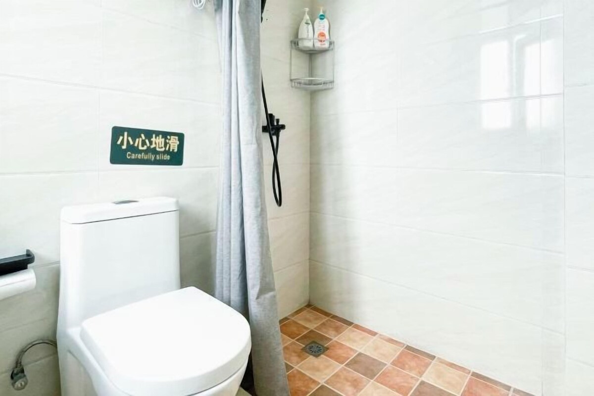A bathroom with a toilet, shower, and tiled walls.