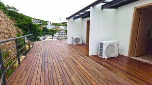 Um deck de madeira com duas unidades de ar condicionado, corrimão e um edifício com porta.