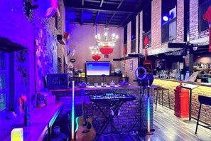 A bar area with a DJ setup, a guitar, and a bar counter.