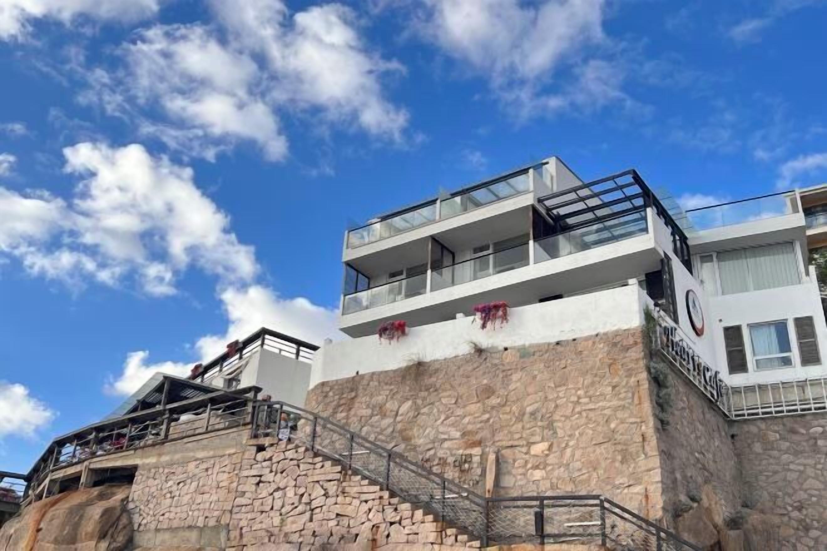 Un immeuble à plusieurs étages, doté d’une façade en pierre, de balcons et d’un escalier menant aux niveaux supérieurs.