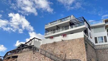 Un immeuble à plusieurs étages, doté d’une façade en pierre, de balcons et d’un escalier menant aux niveaux supérieurs.